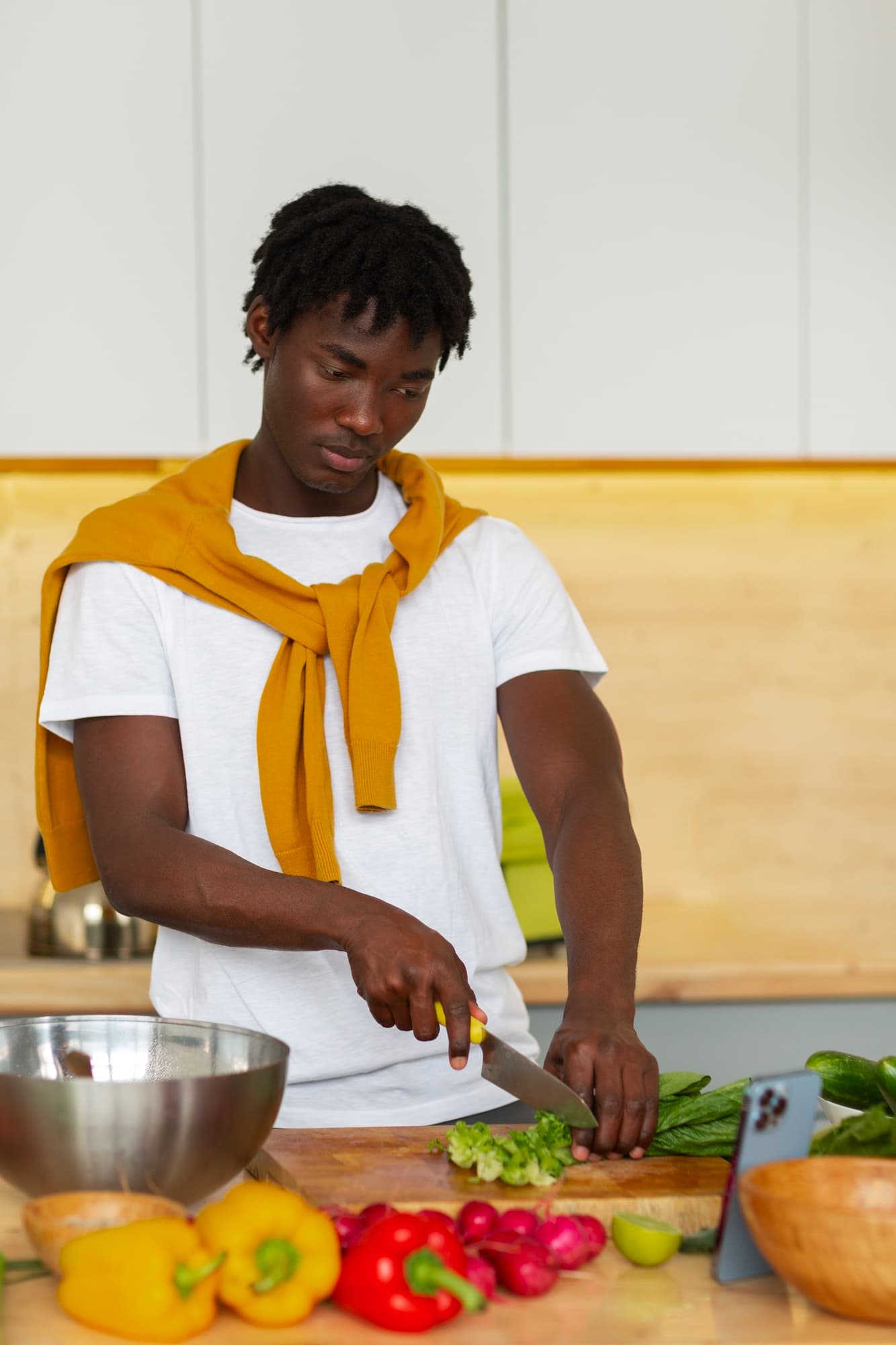 Nigerian fitness enthusiast preparing healthy fresh meal plan with smart phone in kitchen